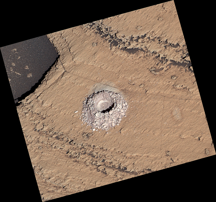 Widoczny z bliska płytki odwiert na jasnobrązowej powierzchni Marsa