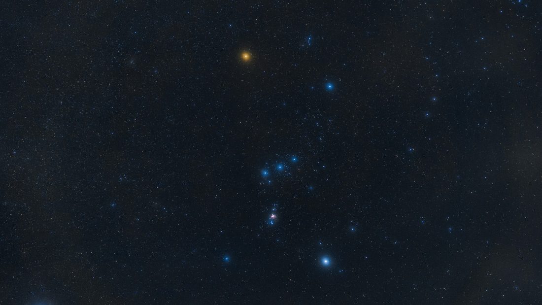 Konstelacja Orion z wyeksponowanymi jasnymi gwiazdami. Wyraźnie widoczna jest żółto-pomarańczowa gwiazda, czyli Betelgeza.