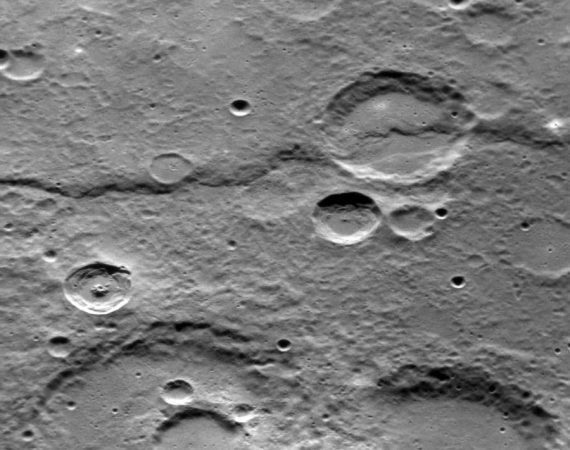 Obrazek czarno-biały. Powierzchnia planety pokryta licznymi kraterami, w połowie zdjęcia wyraźny uskok terenu.