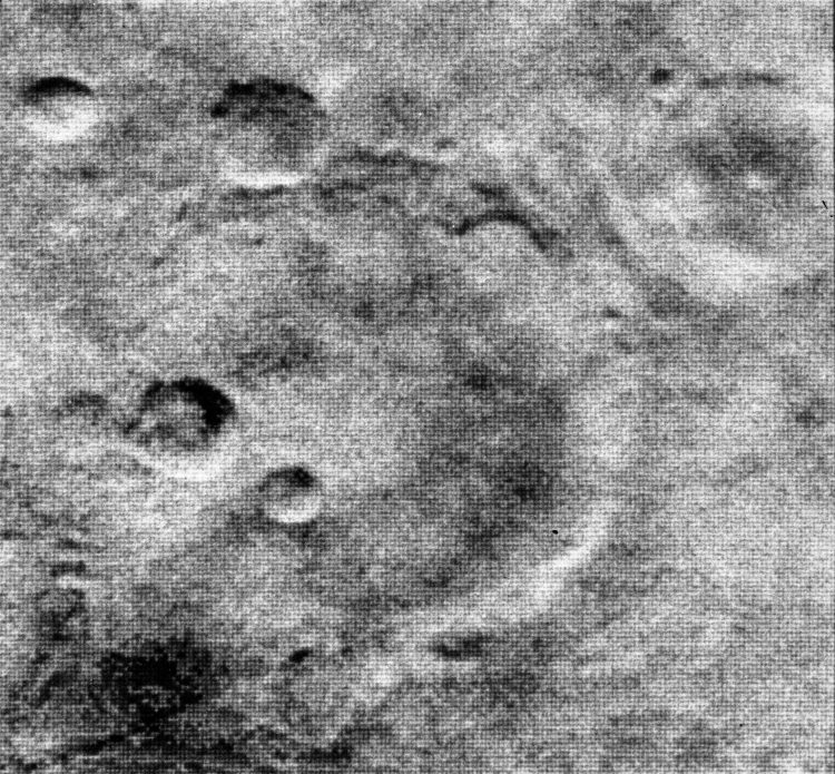 Niskiej jakości czarno-białe zdjęcie powierzchni Marsa przedstawiające cienie ścian kraterów