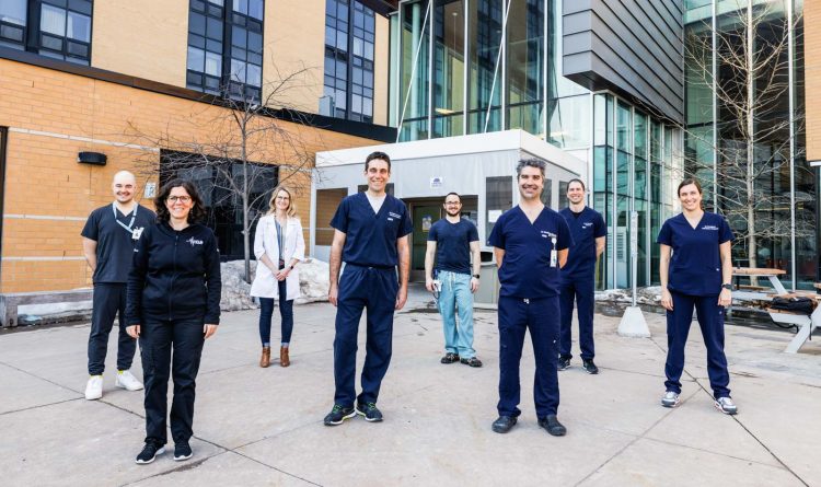 Ośmioro medyków w granatowych ubraniach przed nowoczesnym budynkiem