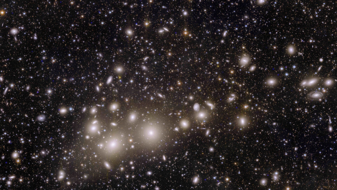 Bardzo duża liczba niewyraźnych galaktyk na tle kosmosu, w dolnym lewym rogu zdjęcia większe jasne punkty