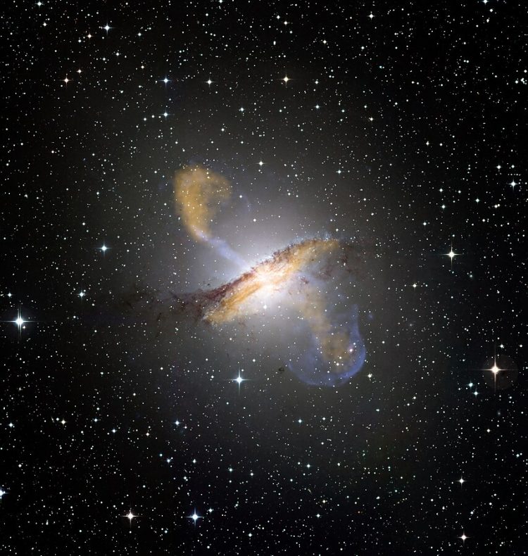 Galaktyka na tle gwieździstego nieba, odwrócona bokiem do obserwatora. Przez jej środek przechodzi jasna pręga w kształcie litery S, prostopadła do płaszczyzny galaktyki