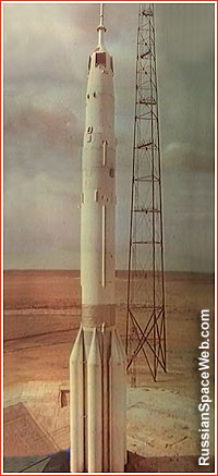 Podłużna biała rakieta na tle kazachskiego stepu i stalowej wieży.