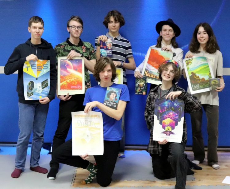 Grupa finalistów wraz z kolorowymi plakatami 