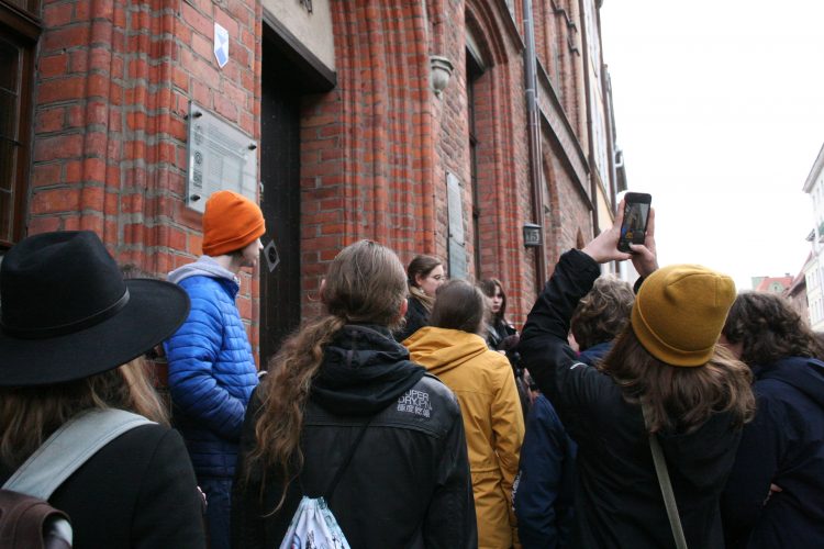 Grupa osób patrzy na budynek z czerwonej cegły