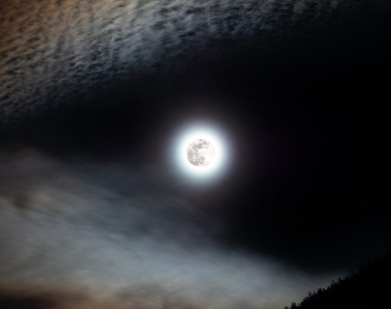 Pełnia Księżyca otoczona z lewej strony chmurami zabarwionymi na pomarańczowo, tworzącymi tzw. "lisią czapę".
