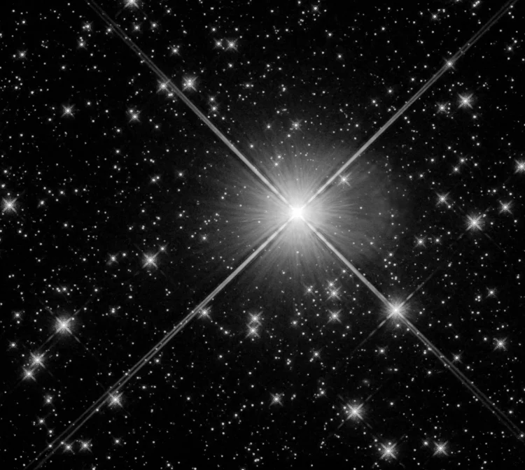 Wiele gwiazd na ciemnym tle z dużą, jasną gwiazdą blisko środka zdjęcia.