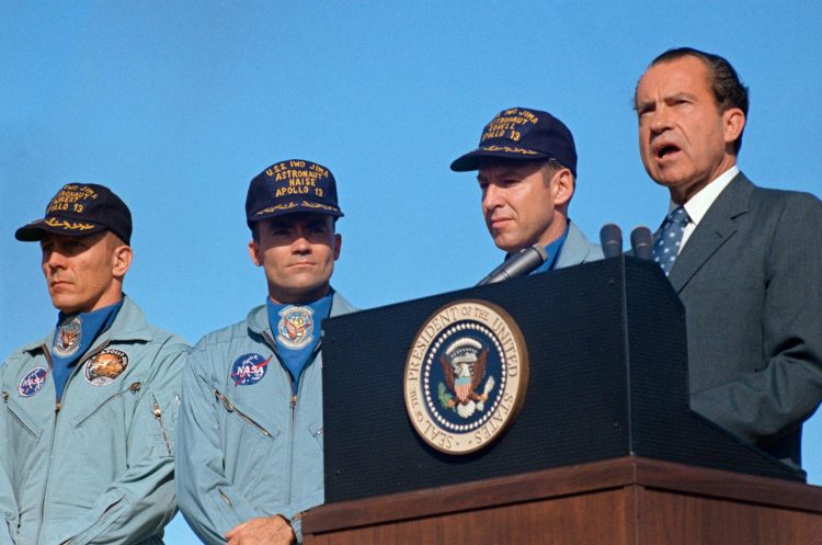 S70-15511 (19 kwietnia 1970) --- Prezydent Richard M. Nixon przemawia w bazie sił powietrznych Hickham przed wręczeniem załodze Apollo 13 najwyższej w kraju nagrody cywilnej. Prezydenckim Medalem Wolności odebrali astronauci James A. Lovell Jr. (obok dyrektora naczelnego), dowódca; John L. Swigert Jr. (po lewej), pilot modułu dowodzenia; oraz Fred W. Haise Jr., pilot modułu księżycowego. Żony Lovella i Haise oraz rodzice Swigerta towarzyszyły Prezydentowi na Hawajach. Rozbicie Apollo 13 nastąpiło o godzinie 12:07:44. (CST), 17 kwietnia 1970, około półtora dnia przed ceremoniami w bazie sił powietrznych Hickam.