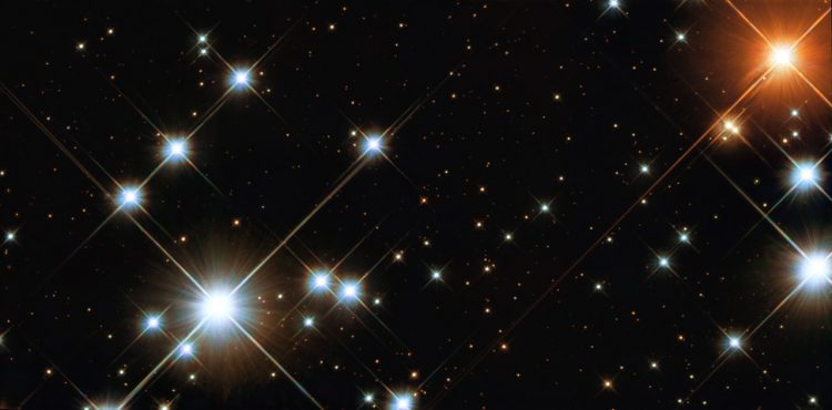 Kilkanaście dużych jasnych niebieskich gwiazd w centrum, w prawym górnym rogu duża czerwona gwiazda.