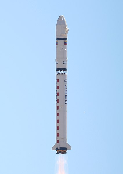 Na jasnoniebieskim tle, ukazana jest biała rakieta z typowym nose cone (czubku w kształcie spłaszczonego stożka) oraz częstą podłużna konstrukcją ze statecznikami na dole. Z boku rakiety narsyowane są flagi Chin oraz różne napisu w języku chińksim.
