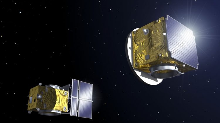 Wizualizacja artystyczna. Na czarnym tle dwie satelity w kształcie sześcianów pokrytych złotą folią z panelami słonecznymi po jednej stronie. 