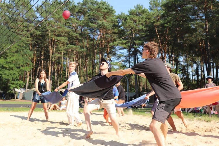 Słoneczny dzień, pośród lasu ,gdzie drużyna kadry rywalizuje z uczestnikami w grze polegającej na przerzucaniu balonu nad siatką na stronę przeciwnika i łapaniu go w ręcznik.