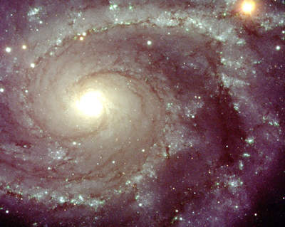Galaktyka spiralna NGC 2997 widziana przez VLT. Złoto-fioletowa spirala z jasnym centrum.